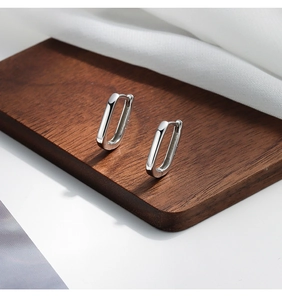 Dettaglio di orecchini a cerchio geometrici in argento sterling S925 lucidato su legno