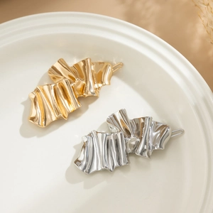 Minimalist irregular gold and silver liquid metal hair clips on a white ceramic plate