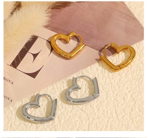 Detail shot of heart-shaped hoop earrings in gold and silver finish on textured surface