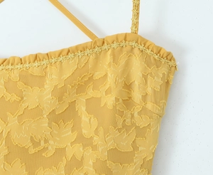 Detailaufnahme von gelber Spitze und zarten Spitzenbesätzen am Oberteil des Kleides
