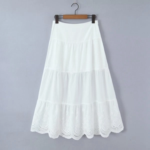 Detailed view of white tiered maxi skirt with intricate hollow embroidery on lace hem
