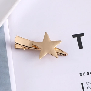 Close-up of a minimalist star-shaped gold metal hair clip with a smooth polished finish