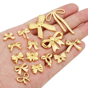Golden stainless steel bow pendants for DIY jewelry making shown in hand for scale