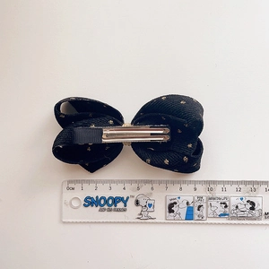 Top view of a black velvet gold-dot bow hair clip with measurement ruler detail
