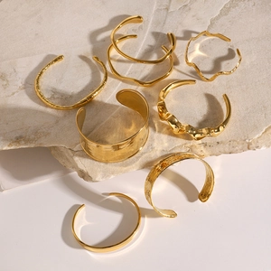 Set of 7 gold-plated irregular geometric bangles with hammered texture and open wave design