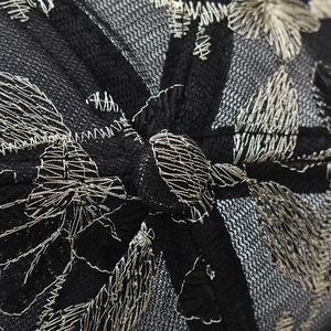 Detail of black lace baseball cap with intricate gold and silver metallic flower embroidery