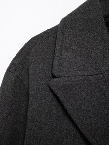 Detailed close-up of dark grey wool blend fabric texture and double-breasted collar seam