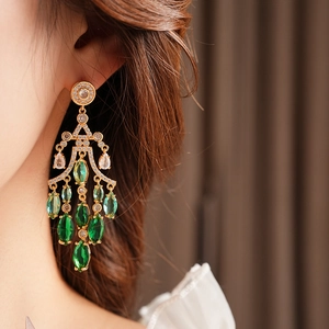 Close-up of gold drop earrings with gradient green zircon crystals on model