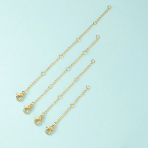 Close-up of four golden stainless steel extender chains with lobster clasps for jewelry