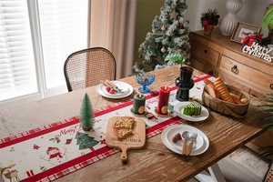 Christmas table runner with snowman patterns and red plaid accents on a festive table