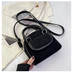 Detail of black suede handbag with plush teddy fur trim and silver metal hardware