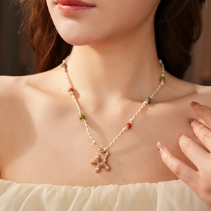 Detail of hand-woven cotton cord necklace featuring ceramic beads and a puppy dog pendant