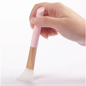 Dettaglio del pennello per maschera facciale con manico rosa e testina a ventaglio in silicone