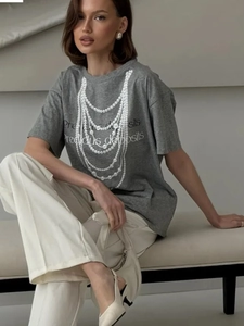 Detail of layered pearl necklace print and graphic text on a grey cotton t-shirt