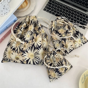 Three-piece drawstring pouch set with yellow daisy print on a navy blue fabric surface
