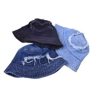 Distressed denim bucket hats in black and blue shades with ripped fringe and stitching