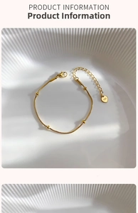 Detail view of 18K gold snake chain bracelet with polished beads and heart charm