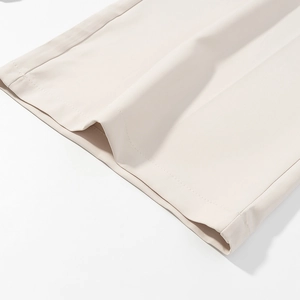 Close-up of beige wide-leg trousers hem with smooth fabric and neat stitching details