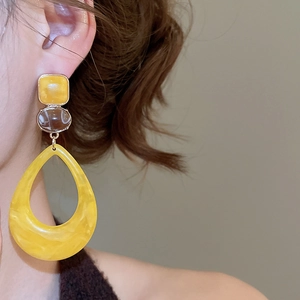 Macro detail of French retro resin drop earrings with yellow and amber geometric pendants