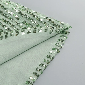Detailed close-up of mint green sequins on mesh fabric for a sequined cocktail dress
