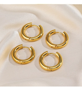 Close-up of four chunky 18K gold plated hoop earrings on soft beige silk fabric