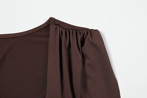 Detailed view of pleated shoulder design on a brown knit dress with soft texture