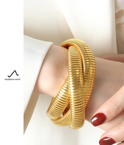 Detail shot of golden triple-layered stainless steel snake bracelet on female wrist