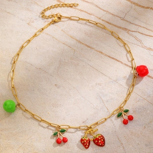 Dettaglio di una collana a catena a graffetta dorata con ciondoli a forma di frutta