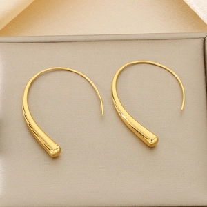Macro shot of minimalist gold drop hook earrings with a polished metallic finish