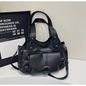 Detail of vintage black faux leather tote featuring decorative buckle and metal rivets