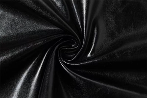 Détail macro du tissu noir brillant avec éclat métallique et texture plissée du set
