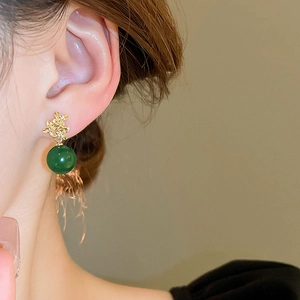 Detail eines Vintage-Goldohrrings mit grüner Harzperle, getragen von einem Modell