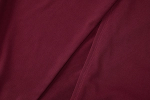 Detailed macro view of the wine red woven fabric texture and high-quality sewing seam