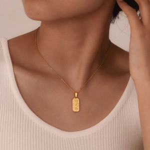 Detail of a vintage gold pendant featuring sun and moon carvings on a cross chain necklace