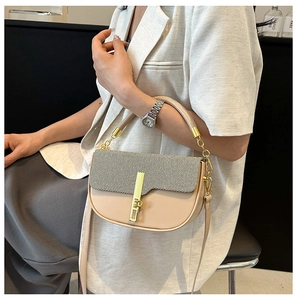 Detail of elegant beige saddle bag with textured flap and gold hardware on white suit