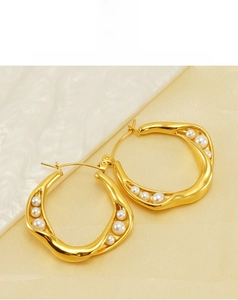 Detailed view of gold twisted earrings with irregular pearls on silk background