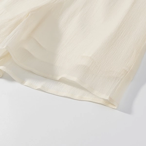 Detailed macro view of the cream white pleated fabric texture and stitching of the dress