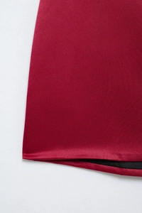Close-up of red satin fabric showing double-layered hem and soft glossy texture on a dress