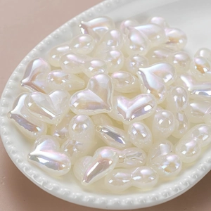 Luminous heart-shaped iridescent beads in a decorative white dish for DIY jewelry