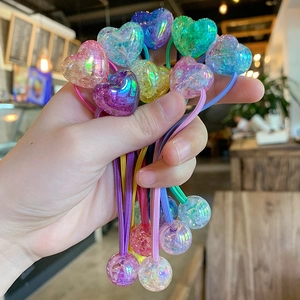 Macro shot of colorful gradient heart and sphere charms on elastic hair ties in hand
