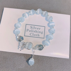 Détail du bracelet en œil de chat bleu clair avec breloque papillon argentée