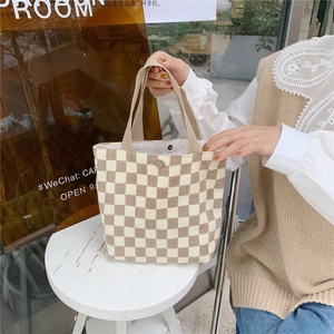 Detail of checkered knit tote bag featuring a metal snap button and woven texture