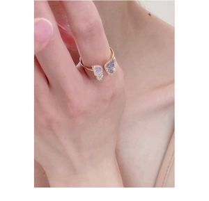 Close-up of a gold butterfly ring with zircon micro-pave details worn on index finger