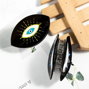 Black acrylic Evil Eye hair claw clips with printed patterns on a decorative background