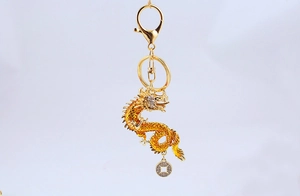 Close-up of golden Chinese dragon keychain with lucky coin and lobster clasp detail