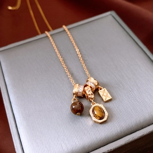Close-up of tiger eye stone pendant necklace with zircon metal ring and geometric charms