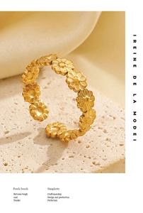 Detailed macro view of gold plated daisy flower chain ring on a textured stone base