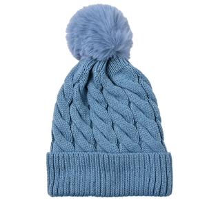Close-up of the blue knitted texture and fluffy faux fur pom-pom on the winter hat