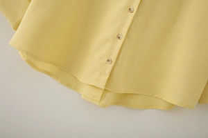 Detail of bright yellow linen shirt showing amber buttons and delicate fabric texture