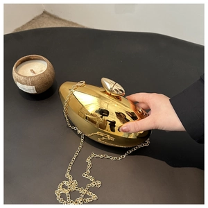 Close-up of golden mango-shaped acrylic evening bag with metallic chain strap